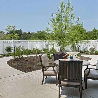 A cozy backyard patio with a table and chairs surrounded by a landscaped garden.