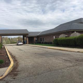 A view of a building with an extended driveway under a cloudy sky.