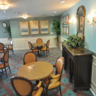 A cozy dining area with round tables, cushioned chairs, decorative artwork, and a mirror on the wall.