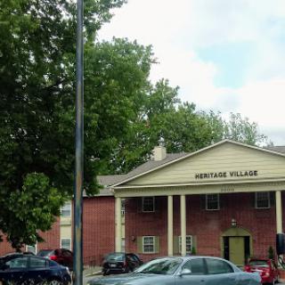 A view of the residential building named 'Gertman Village' surrounded by greenery and parked cars.