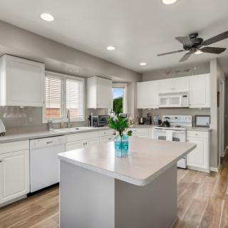 A modern kitchen with white cabinets, a central island, and wooden flooring.