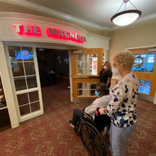 A woman assists another person in a wheelchair at the entrance of a restaurant.