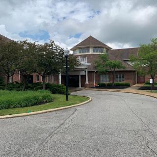 A serene view of a well-designed building surrounded by lush greenery and a winding pathway.