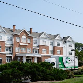 A multi-story residential building with a moving truck parked in front.