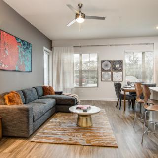 A modern living room with a comfortable sofa, stylish coffee table, and vibrant artwork, seamlessly connecting to a dining area.