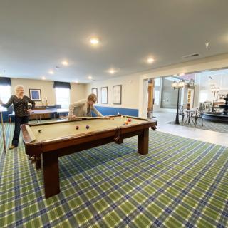 Two people enjoying a game of pool in a recreational room.