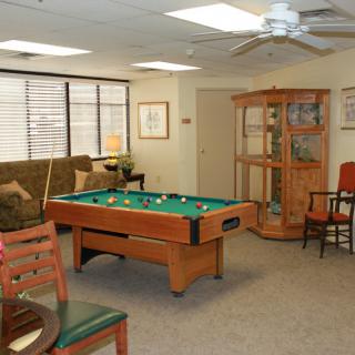 A cozy game room featuring a pool table, sofa, and various chairs.