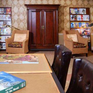 Cozy library room with armchairs, a table, and bookshelves.