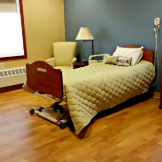 A minimalist hospital room with a single bed and chair.