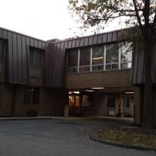 A view of a modern architectural building featuring large windows and a metal roof.