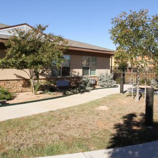 A residential home with a front yard and pathway under a clear blue sky.