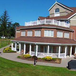 A multi-story house with a spacious yard and garden, featuring large windows and a wrap-around porch.
