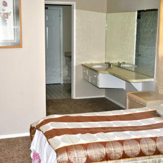 A cozy bedroom with a view of the attached bathroom, featuring a double sink and mirror.