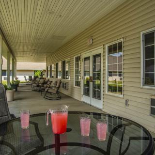 A peaceful patio setting with rocking chairs and drinks on a glass table.