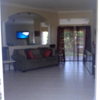 A spacious living room with a sofa, television, and large windows.