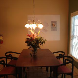 A cozy dining room with a wooden table, elegant chandelier, and a vase of flowers.