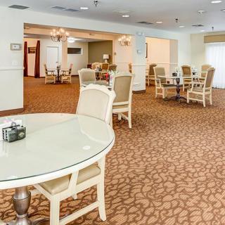 A spacious dining area with several tables and chairs, featuring a carpeted floor and soft lighting.