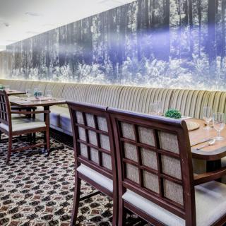 A chic restaurant dining area with stylish chairs and tables, featuring a large wall mural and patterned floor tiles.