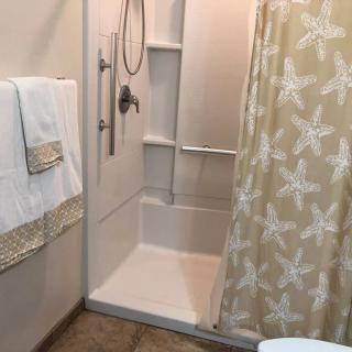 A neatly arranged bathroom featuring a shower with a starfish-patterned curtain and folded towels.