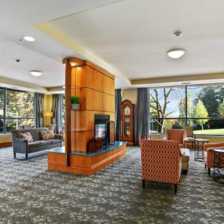 A modern lounge area featuring comfortable seating, a fireplace, and large windows with scenic views.