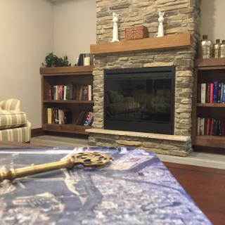 A cozy living room with a stone fireplace, wooden bookshelves, and a decorative table centerpiece.