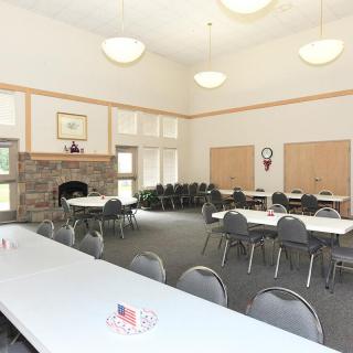 A spacious conference room with tables, chairs, and a fireplace.