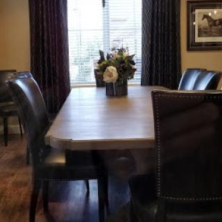 A cozy dining room featuring a wooden table, leather chairs, and a floral centerpiece.