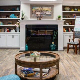 A cozy living room with a central fireplace, surrounded by bookshelves and a round coffee table.