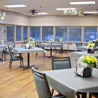 A well-arranged dining area with tables and chairs adorned with white tablecloths and floral centerpieces.