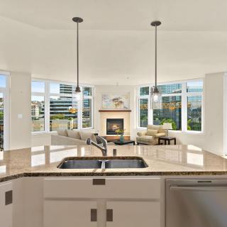 A modern open-concept kitchen and living room with large windows and pendant lighting.