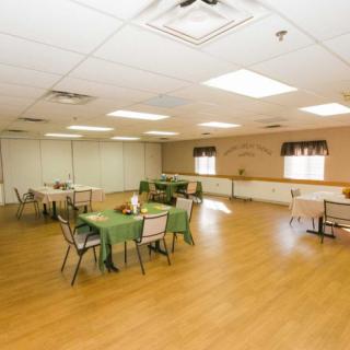 An empty event space with tables and chairs arranged on a wooden floor.