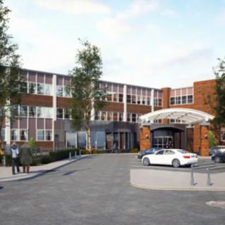 A modern building with a welcoming entrance and parked cars in front.