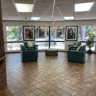 A cozy seating area in a well-lit lobby featuring artwork and views of the outdoors.
