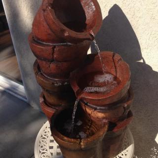A vintage-style ceramic fountain with water cascading through stacked pots.