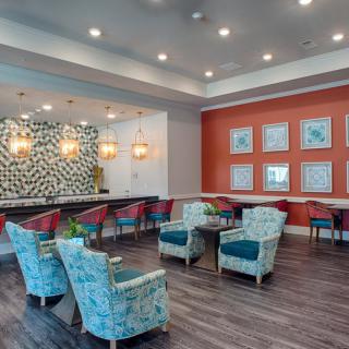 A modern lounge area with colorful seating, interesting wall art, and elegant lighting.