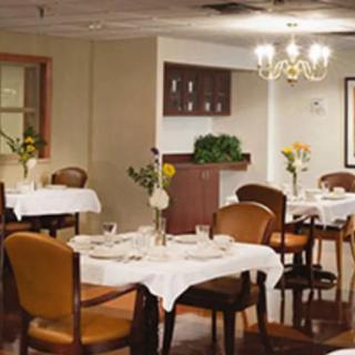 A cozy restaurant dining area with neatly arranged tables and chairs, adorned with flowers and a chandelier.