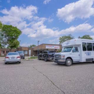 Vehicles parked in a lot outside a commercial building under a partly cloudy sky.