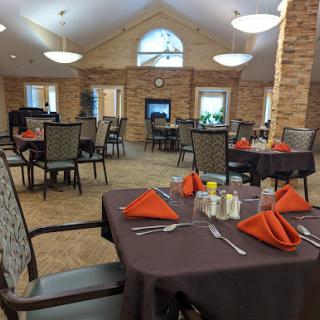 A cozy dining area set up for a meal, featuring neatly arranged tables and vibrant orange napkins.
