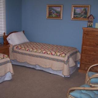 A cozy bedroom with two twin beds, blue walls, and a wooden dresser.