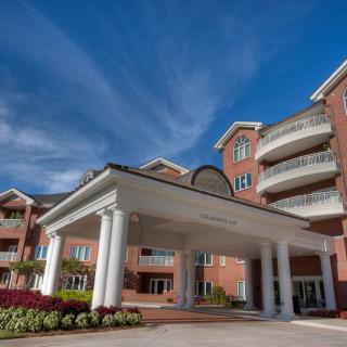 A large residential building with a grand entrance and brick exterior against a partly cloudy sky.