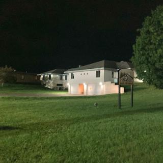 A peaceful night scene featuring a house illuminated against the dark sky.