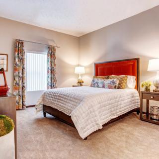 A cozy bedroom with a large bed, bedside lamps, and decorative elements.