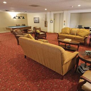 A cozy lounge area with sofas, armchairs, and a pool table in the background.