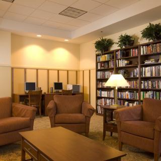 A cozy library with bookshelves, computers, and comfortable seating.