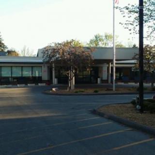 A building entrance with a surrounding parking lot and landscaped area.