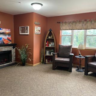 A cozy living room featuring comfortable chairs, a fireplace, and decorative elements.
