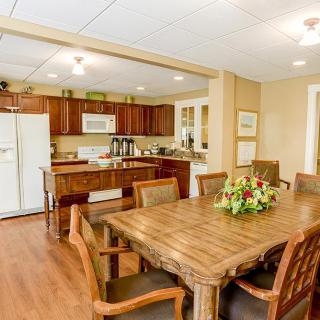 A spacious kitchen and dining area featuring a large wooden table with chairs, a refrigerator, and stylish cabinets.