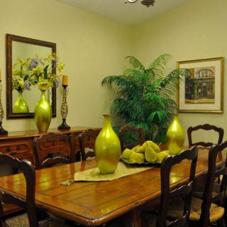 A stylish dining room with wooden furniture and green decorative elements.