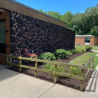 A well-maintained garden alongside a brick building featuring a textured stone wall.