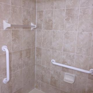 A tiled shower area equipped with safety grab bars.